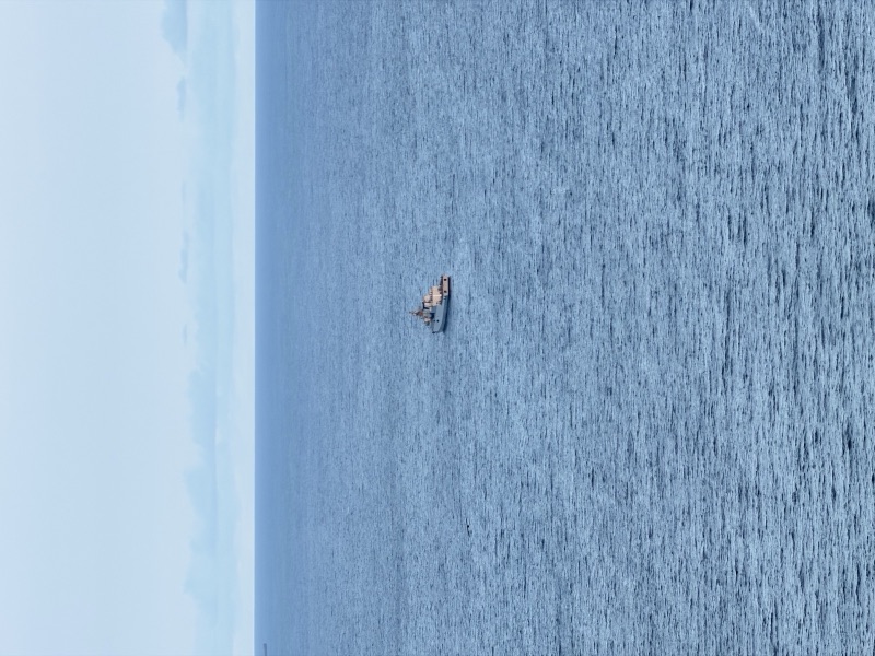 A lone ship on a vast deep-blue ocean